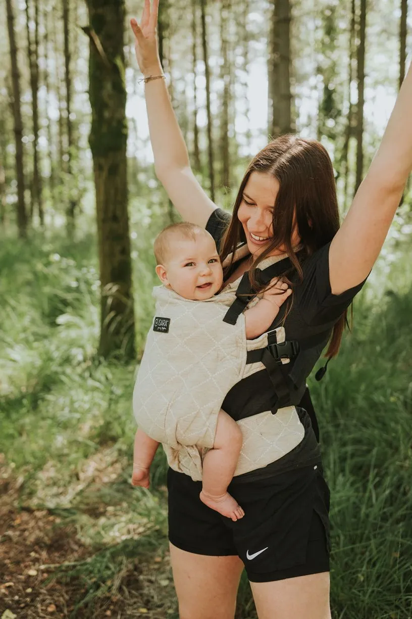 Mama danst in het bos met haar baby in een draagzak